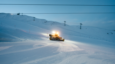 Eine Pistenraupe bereitet in der Abenddämmerung die Skipisten von Gargellen im Montafon vor. Die Scheinwerfer leuchten über die frisch präparierte Schneefläche, im Hintergrund sind die Skilifte und verschneiten Hänge zu sehen. | © Montafon Tourismus GmbH, Marie Schilcher